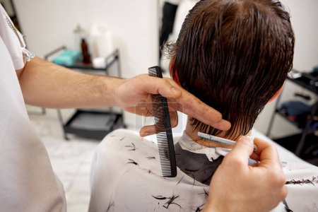 Foto de Peluquería hace corte de pelo para el hombre caucásico en la peluquería. primer plano - Imagen libre de derechos