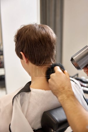 Téléchargez les photos : Young caucasian man getting haircut by professional male hairstylist at barber shop. - en image libre de droit