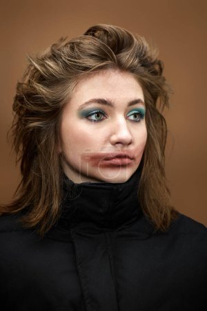 Foto de Retrato de mujer con lápiz labial manchado y peinado elegante en chaqueta negra sobre fondo beige. chica desafiante - Imagen libre de derechos