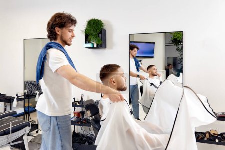Téléchargez les photos : Professional barber during work with man client in barber shop. - en image libre de droit