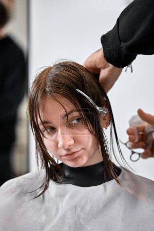 Téléchargez les photos : Professional male hairdresser with scissors cutting female hair in salon - en image libre de droit