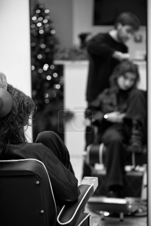 Foto de Beautiful young woman in modern hair salon. hairdresser checking hairstyle of caucasian girl - Imagen libre de derechos