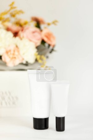 Téléchargez les photos : Tube de bouteille blanc pour produit cosmétique de beauté avec ingrédient naturel et fleur. maquette - en image libre de droit