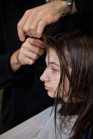 Foto de Male hairdresser is combing the hair of the female client. hairdresser doing hair to his client woman - Imagen libre de derechos