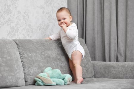 Foto de Lindo bebé chica jugando con suave juguete conejito en casa. - Imagen libre de derechos