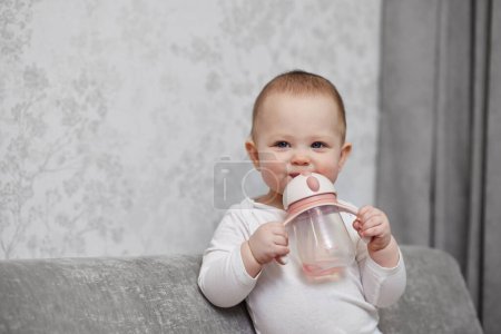Foto de Niña sosteniendo la botella y bebiendo agua en casa. - Imagen libre de derechos