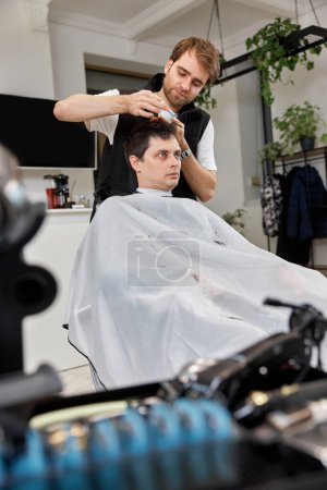 Photo for Hairstylist serving handsome caucasian man in barber shop. - Royalty Free Image