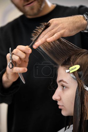 Photo for Professional male hairdresser with scissors cutting female hair in salon - Royalty Free Image