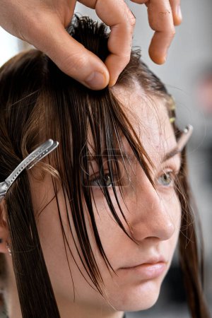 Foto de Professional male hairdresser cutting female hair in salon - Imagen libre de derechos