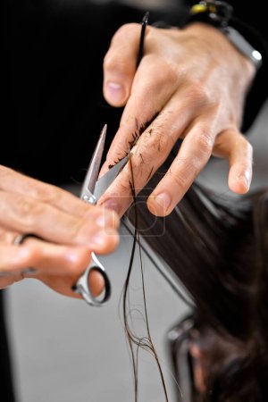 Téléchargez les photos : Professional male hairdresser with scissors cutting female hair in salon - en image libre de droit