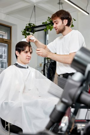 Photo for Handsome young man visiting professional hairstylist in barber shop - Royalty Free Image