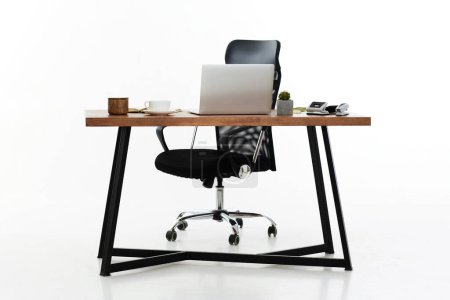 Foto de Cómoda silla de oficina cerca de la mesa con computadora portátil moderna aislada sobre fondo blanco - Imagen libre de derechos