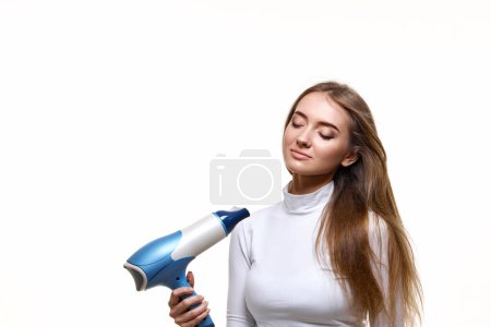 Téléchargez les photos : Belle jeune femme séchage forte cheveux sains avec sèche-cheveux i isolé sur fond blanc - en image libre de droit