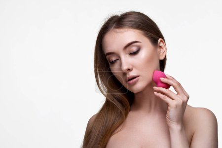 Téléchargez les photos : Attrayant jeune femme en utilisant des éponges cosmétiques roses isolés sur fond blanc. espace de copie - en image libre de droit