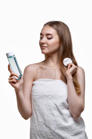 Téléchargez les photos : Belle femme tenant bouteille avec tonique, nettoyage de la peau avec du coton. Concept beauté et soin de la peau - en image libre de droit