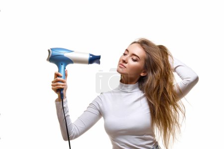 Photo for Attractive cheerful lady drying long hair isolated on white background - Royalty Free Image