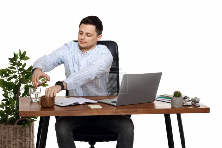 Téléchargez les photos : Homme d'affaires en chemise bleue prenant des notes, en utilisant un ordinateur portable sur fond blanc - en image libre de droit