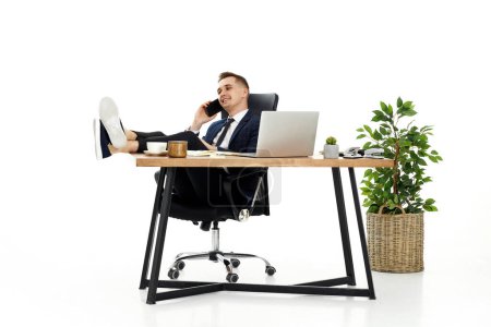 Téléchargez les photos : Un homme d'affaires heureux qui travaille avec un ordinateur portable et qui a une conversation téléphonique avec un client - en image libre de droit