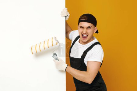 Foto de Hombre muy emocionado en ropa de trabajo pintando paredes blancas en la habitación. espacio de copia para texto - Imagen libre de derechos
