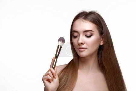 Foto de Atractiva mujer con cepillo de maquillaje para polvo aislado sobre fondo blanco - Imagen libre de derechos