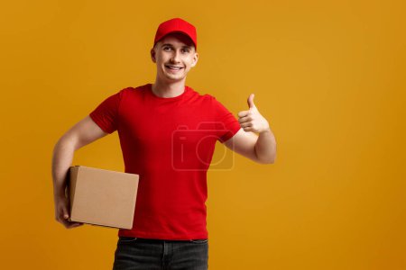 Photo for Smiling delivery man employee in red cap, t-shirt holding cardboard box isolated on orange background - Royalty Free Image