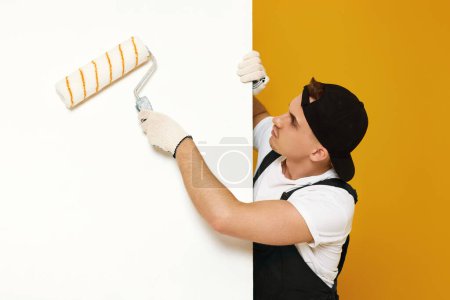 Foto de Joven con ropa de trabajo pintando paredes blancas en la habitación. espacio de copia para texto - Imagen libre de derechos