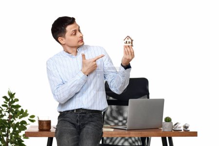 Téléchargez les photos : Succès caucasien homme d'affaires tenant maison jouet dans le bureau. assurance immobilière - en image libre de droit