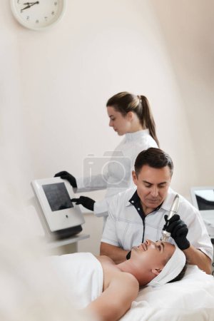 Photo for Handsome man on RF lifting procedure in aesthetic medicine clinic - Royalty Free Image