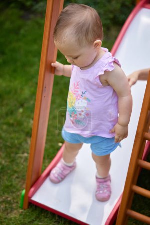 Photo for Baby girl playing slider in playground in the summer - Royalty Free Image