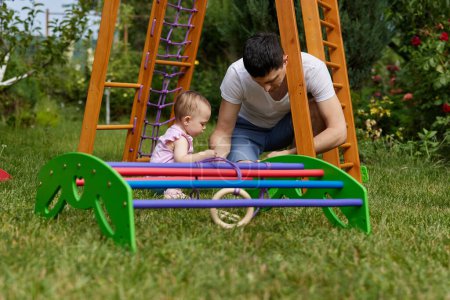 Téléchargez les photos : Papa avec petite fille enfant fille recueille en bois maison complexe sportif en plein air. processus d'assemblage - en image libre de droit