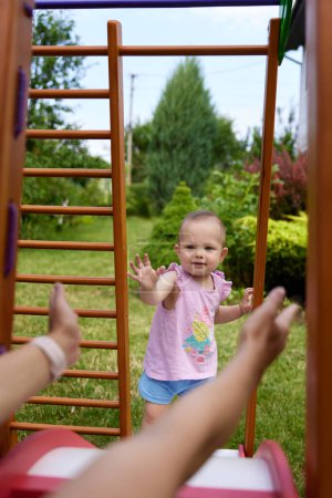 Photo for Little baby girl with mother playing on slide in playground in summer. Summer family leisure. - Royalty Free Image