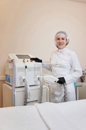 Téléchargez les photos : Femme médecin cosmétologue avec laser, épilation avec équipement moderne - en image libre de droit