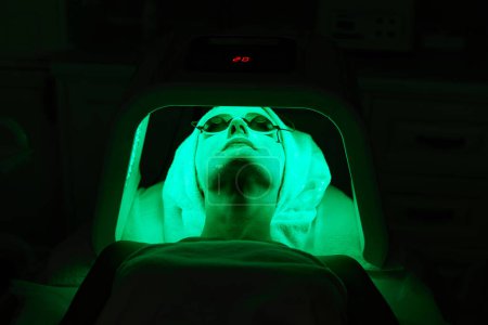 Photo for Woman in protective glasses getting facial treatment with led therapy. LED mask at the beauty clinic - Royalty Free Image