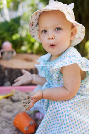 Foto de Feliz niña emocionada jugando en arena en caja de arena con varios juguetes en el patio al aire libre - Imagen libre de derechos