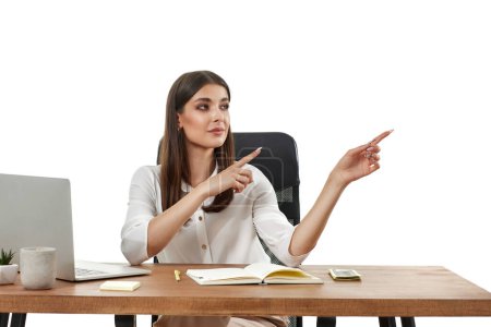 Téléchargez les photos : Femme d'affaires positive en utilisant un ordinateur portable et pointant vers l'espace de copie sur fond blanc - en image libre de droit