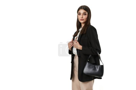 Téléchargez les photos : Belle femme avec sac en blazer noir et pantalon beige isolé sur fond blanc. espace de copie - en image libre de droit