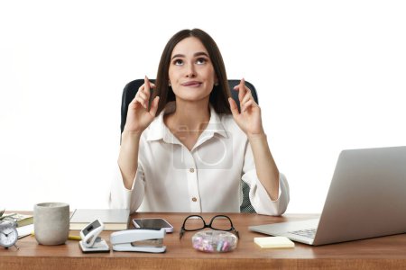 Téléchargez les photos : Belle femme d'affaires en utilisant un ordinateur portable et montrant les doigts croisés pour la bonne chance - en image libre de droit