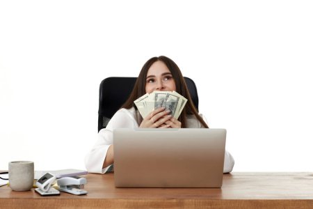 Foto de Feliz dama de negocios que trabaja en el ordenador portátil y la celebración de dinero en la cara - Imagen libre de derechos