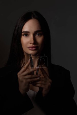 Téléchargez les photos : Beauté professionnel femme tenant pinces tout en posant sur fond noir - en image libre de droit
