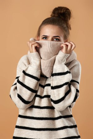 Photo for Young pretty woman wearing knitted sweater and scarf posing on beige background - Royalty Free Image