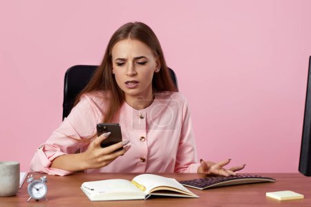 Foto de Enojado molesto mujer de negocios nerviosa usando el teléfono sobre fondo rosa - Imagen libre de derechos
