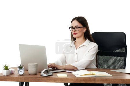 Téléchargez les photos : Belle gestionnaire féminin en utilisant ordinateur portable pour le travail en ligne à la table - en image libre de droit