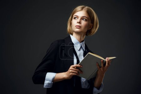 Foto de Mujer de negocios rubia de moda sosteniendo bloc de notas aon fondo negro. espacio de copia - Imagen libre de derechos