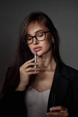 Téléchargez les photos : Beauté professionnel sexy femme tenant pince à épiler tout en posant sur fond noir - en image libre de droit