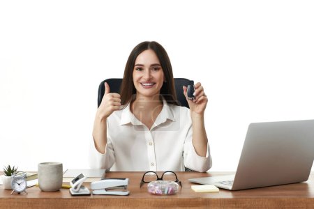 Téléchargez les photos : Happy manager femme montrant pouces vers le haut signe geste assis au bureau et en utilisant un ordinateur portable - en image libre de droit
