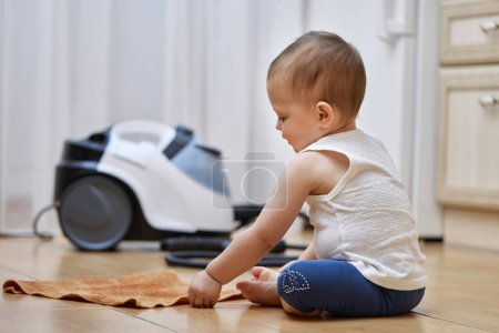 Téléchargez les photos : Petite fille bébé avec un chiffon laver le sol carrelé, mignon petit assistant - en image libre de droit