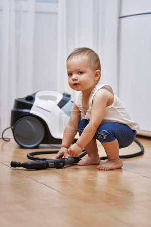 Téléchargez les photos : Petit bébé fille jouer avec professionnel nettoyage générateur de vapeur, mignon petit assistant - en image libre de droit