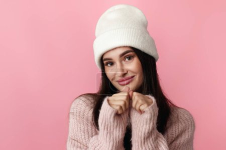 Photo for Cute woman in white hat, pink sweater looking at the camera on pastel pink background. - Royalty Free Image