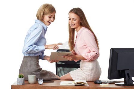 Foto de Dos trabajadoras de oficina discuten el proyecto, sentadas en el escritorio con el portapapeles en la oficina - Imagen libre de derechos