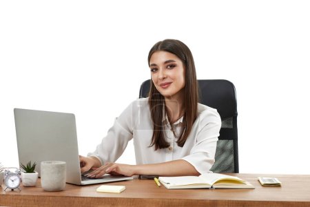 Téléchargez les photos : Belle gestionnaire féminin en utilisant un ordinateur portable pour le travail en ligne à table sur fond blanc - en image libre de droit